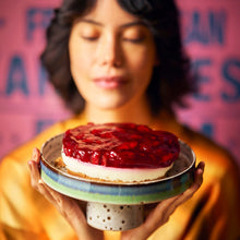 Load image into Gallery viewer, woman holding cake stand with cheesecake and strawberries
